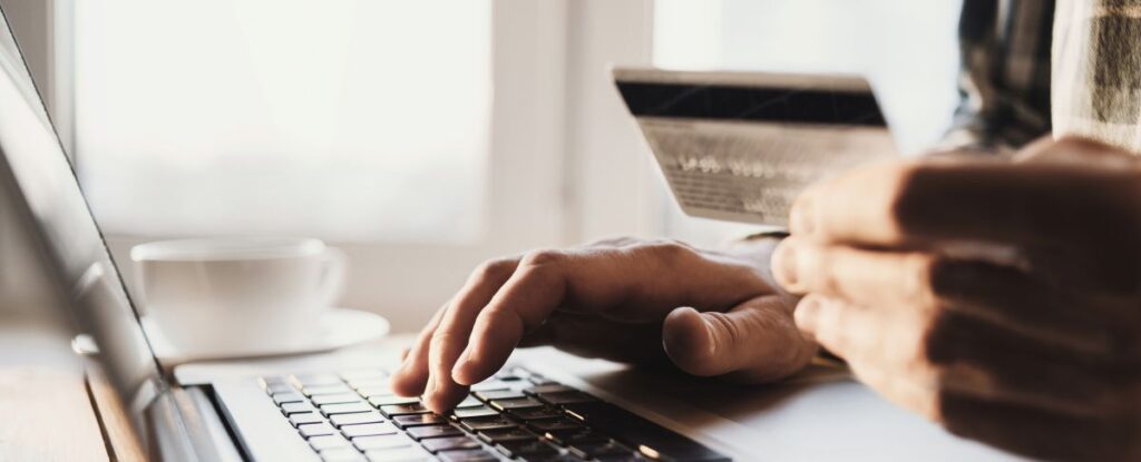 person using a credit card with a laptop