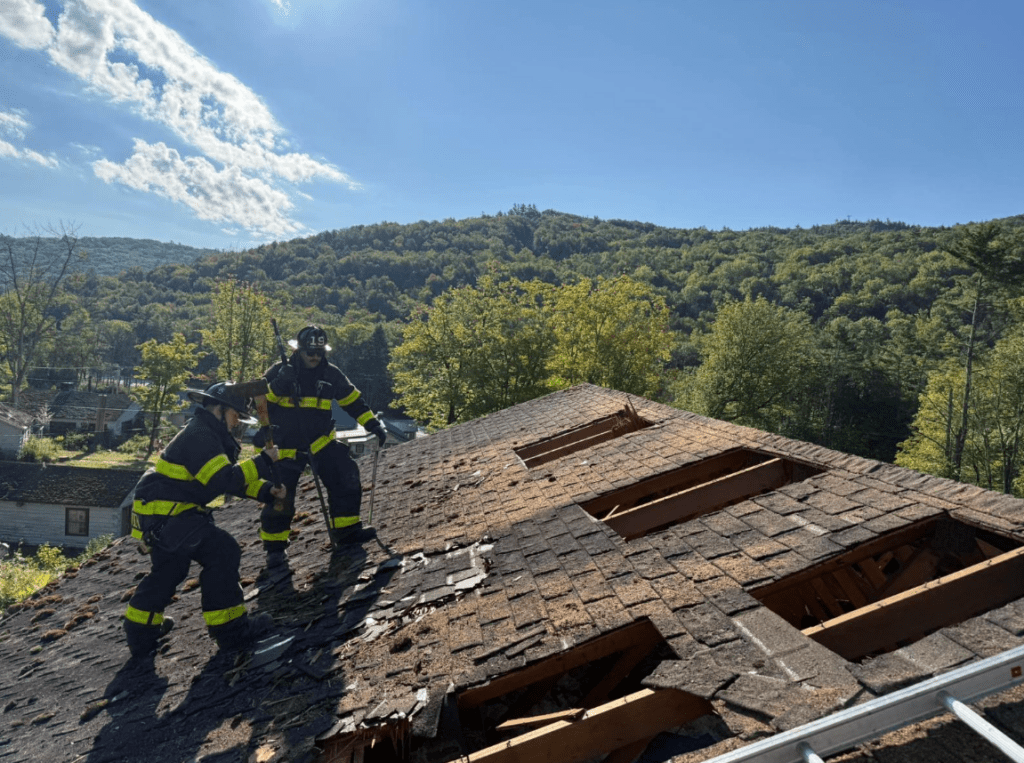 Two firefighters on top of a roof