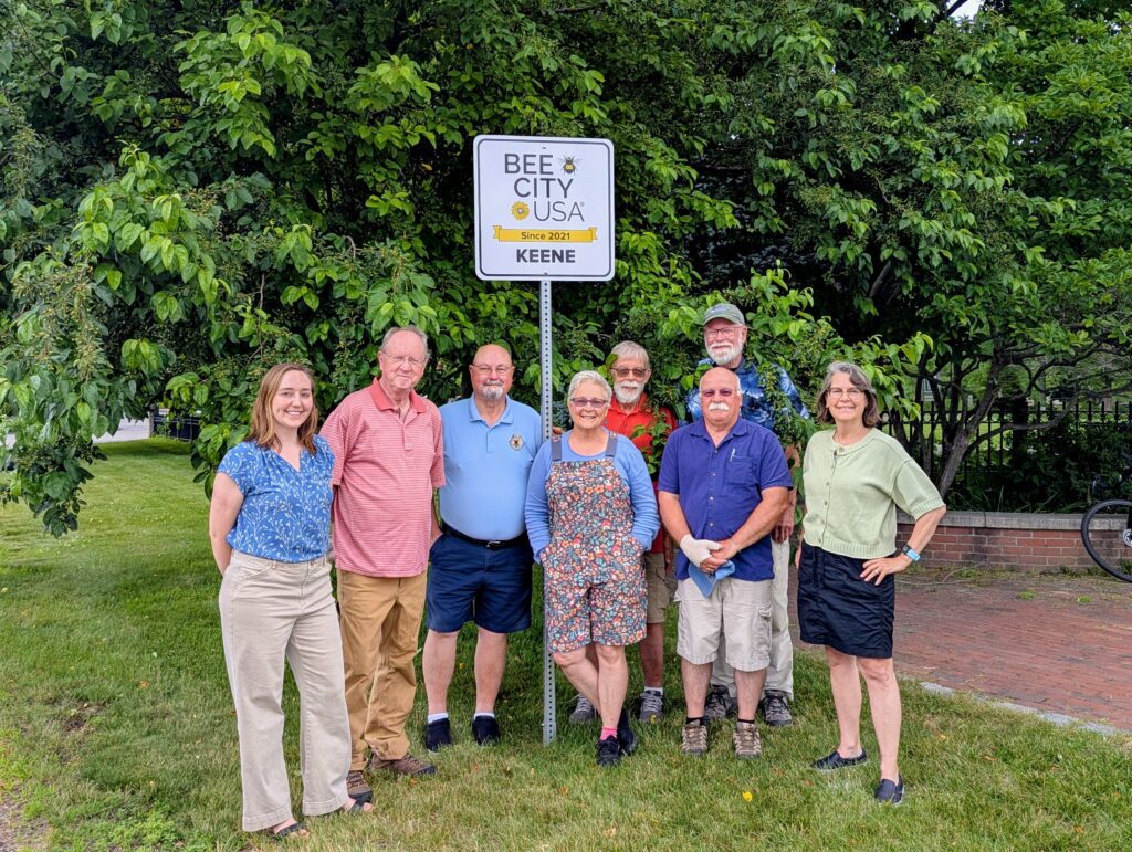 Group photo of the Keene Conservation Commission standing in front of a "Bee City USA" sign.